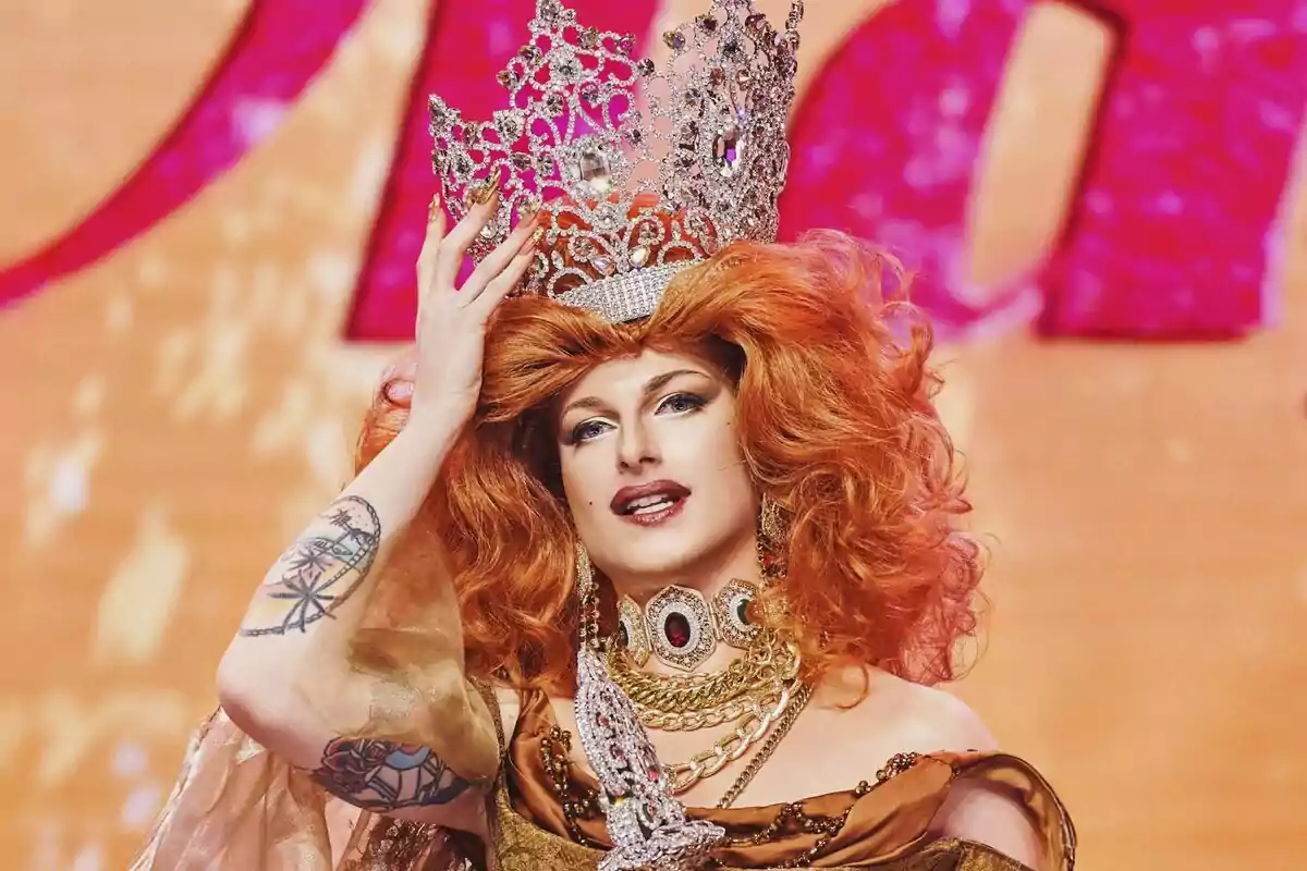 Le Cocó amb perruca vermella i corona brillant en un escenari colorit a Drag Race España.