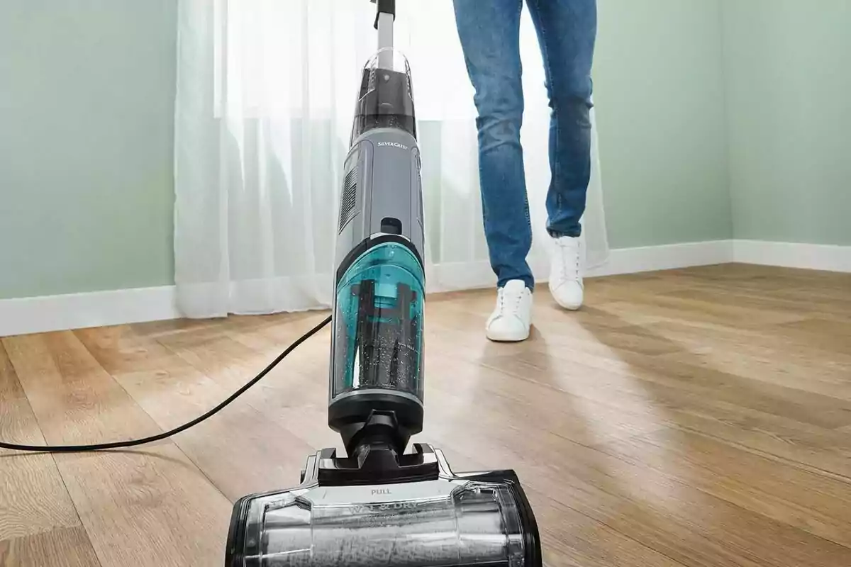 Person using a vacuum cleaner on a wooden floor in a well-lit room. Person using a vacuum cleaner on a wooden floor in a well-lit room.