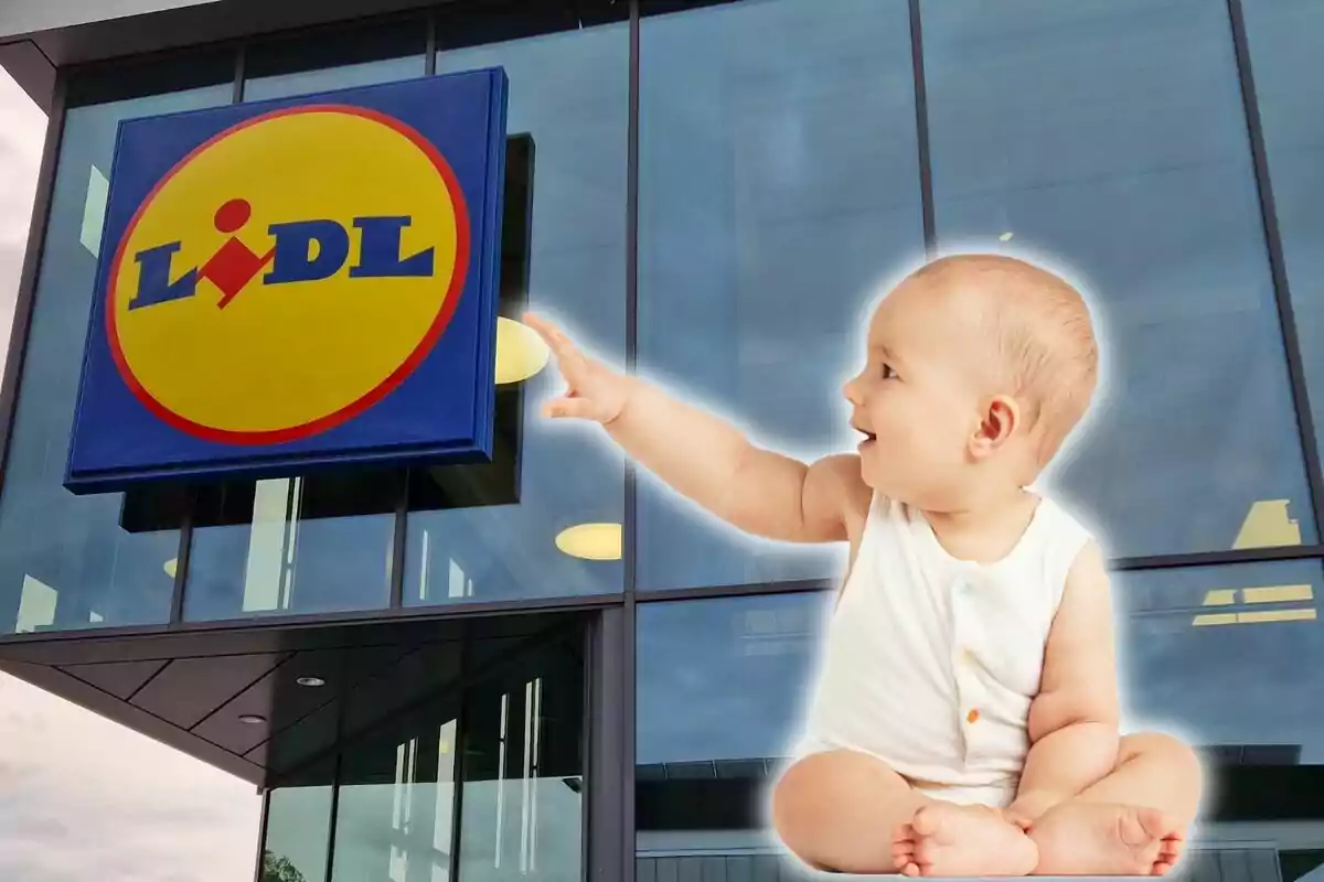 Un nadó assegut i somrient mentre assenyala el logotip de Lidl a la façana d?una botiga.