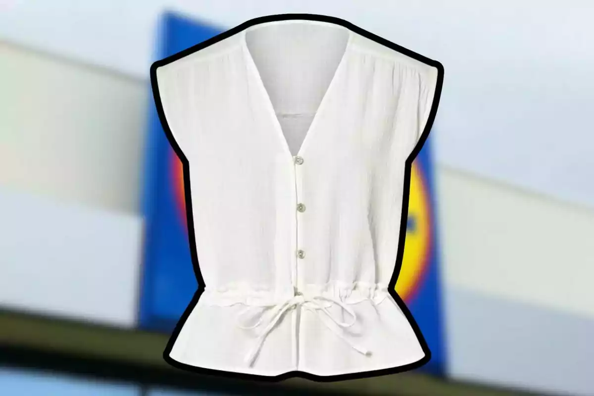Brusa blanca sense mànigues amb botons i llaç a la cintura sobre un fons desenfocat d’una botiga Brusa blanca sense mànigues amb botons i llaç a la cintura sobre un fons desenfocat d’una botiga