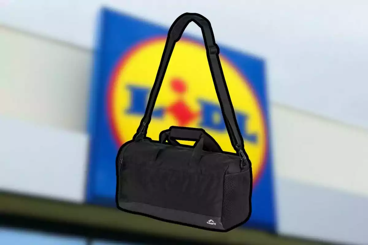 Una bossa d'esport negra amb corretja ajustable davant d'un fons desenfocat d'un logotip de supermercat. Una bossa d'esport negra amb corretja ajustable davant d'un fons desenfocat d'un logotip de supermercat.