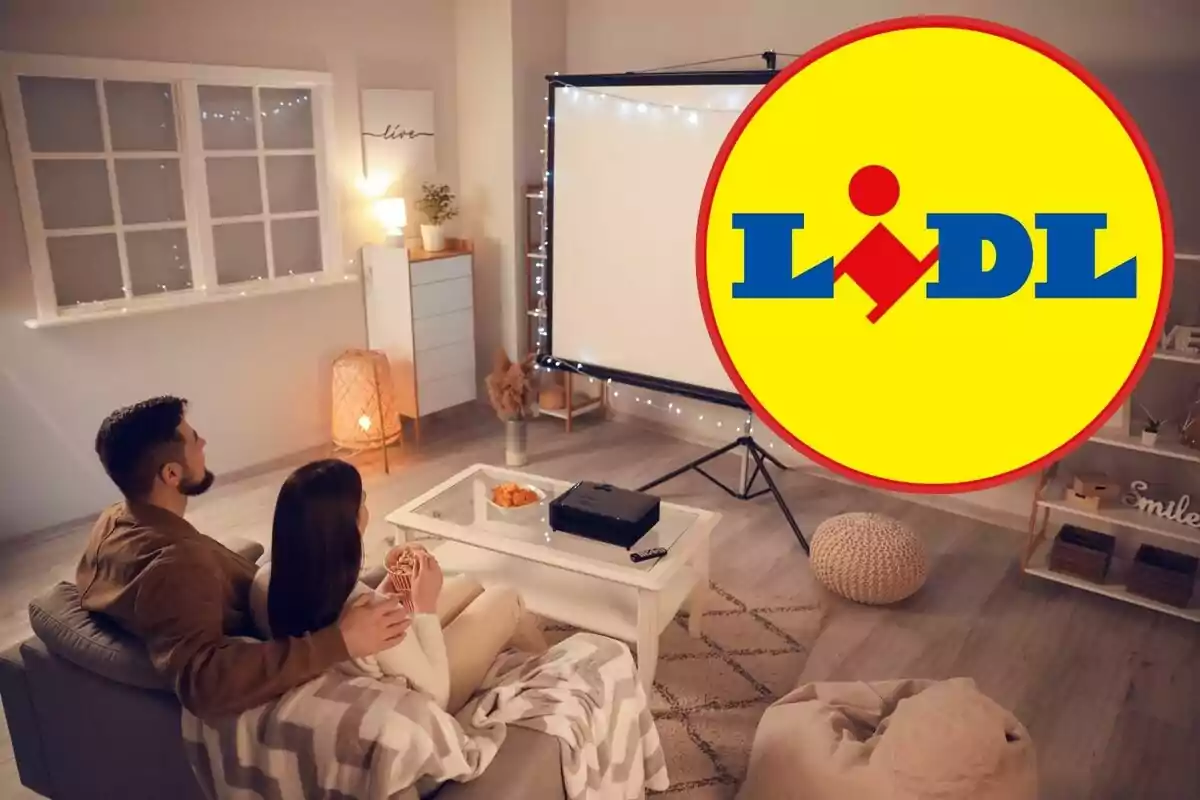 Una parella asseguda en un sofà veient una projecció en una sala acollidora amb decoració moderna i el logotip de Lidl superposat a la imatge.