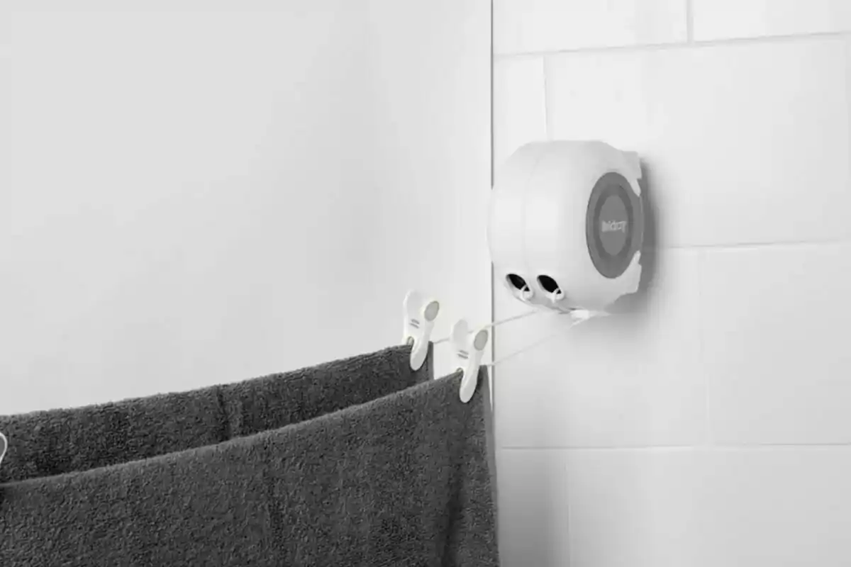 Wall-mounted retractable cord device with a gray towel hanging. Wall-mounted retractable cord device with a gray towel hanging.