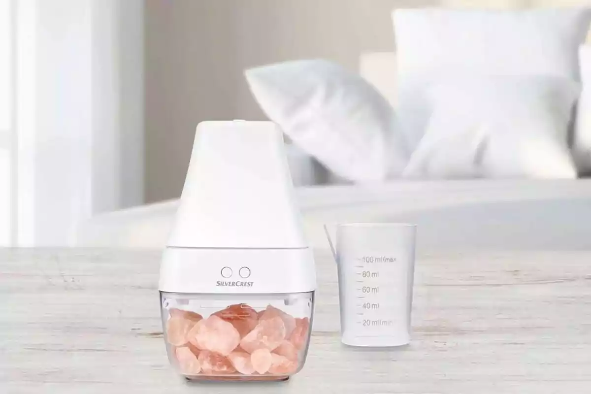 A modern design salt grinder and a measuring cup on a light wooden table with a blurred bed background. A modern design salt grinder and a measuring cup on a light wooden table with a blurred bed background.