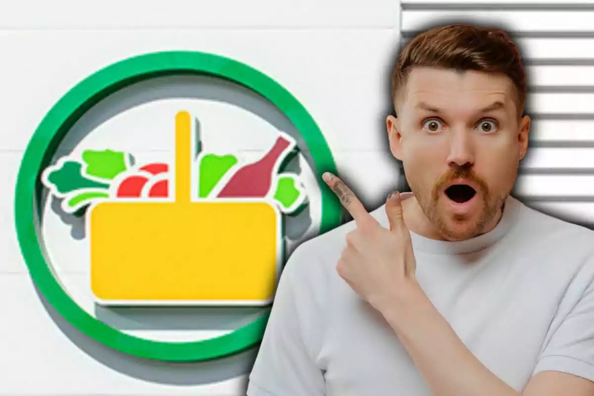 Un home sorprès assenyala un logotip de supermercat amb una cistella de la compra plena d'aliments.