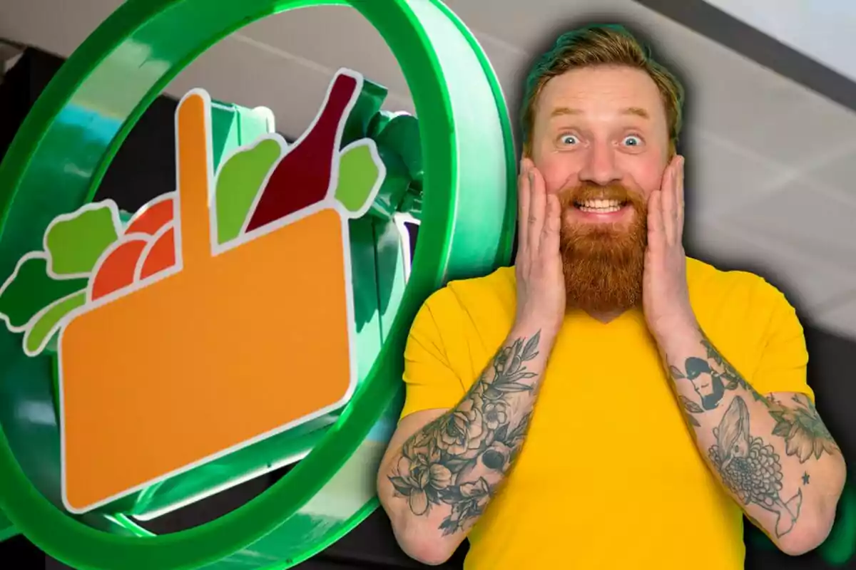 Home amb barba i tatuatges somriu sorprès davant d’un rètol de supermercat amb fruites i una ampolla