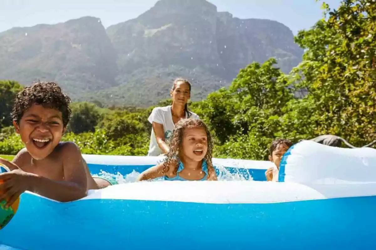 Un grup de nens juga i es diverteix en una piscina inflable a l'aire lliure amb muntanyes i vegetació de fons. Un grup de nens juga i es diverteix en una piscina inflable a l'aire lliure amb muntanyes i vegetació de fons.