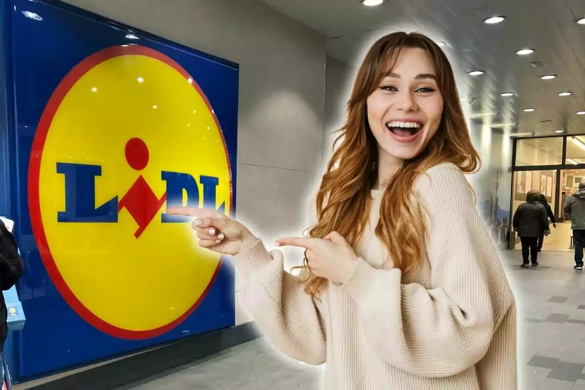 A smiling woman with long light brown hair, dressed in a beige sweater, points with both hands at the Lidl logo at the entrance of a store.