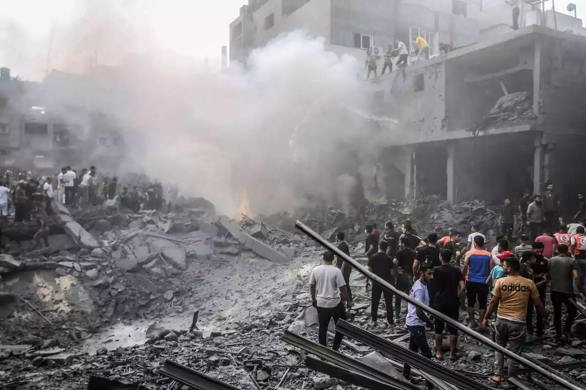 La gent apaga un incendi al lloc dels atacs aeris israelians mentre continuen els combats entre les tropes israelianes i els militants islamistes de Hamàs.