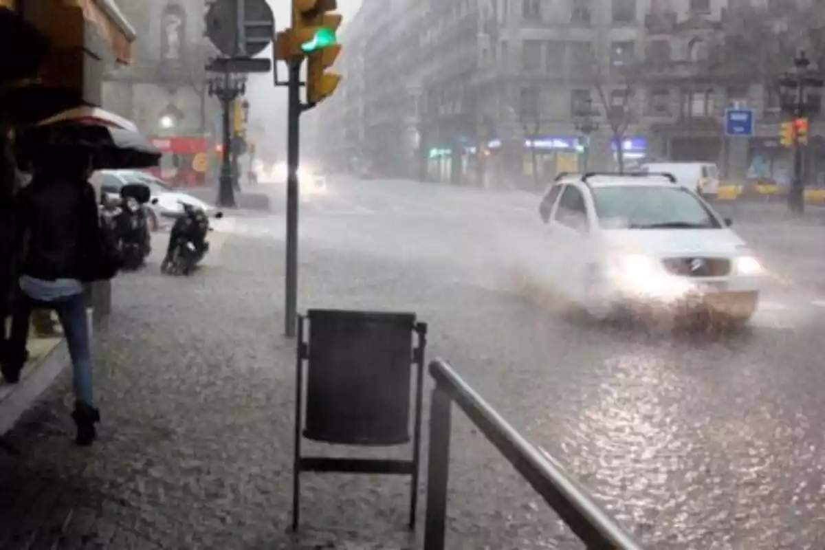 Imagen de un coche circulando por Barcelona con las calles inundadas