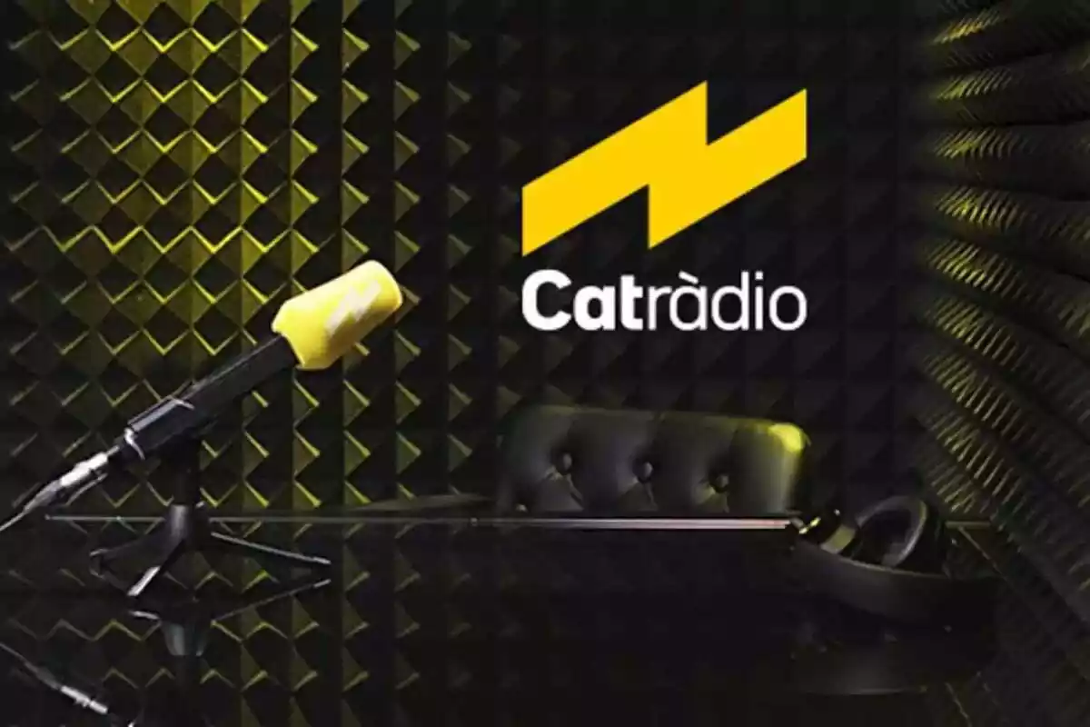 Imatge d´un estudi de ràdio amb les parets negres, igual que la taula i la cadira que apareixen, i un micro a la taula amb l´escuma característica de Catalunya Ràdio. A la part superior dreta, el nou logo de Catalunya Radio