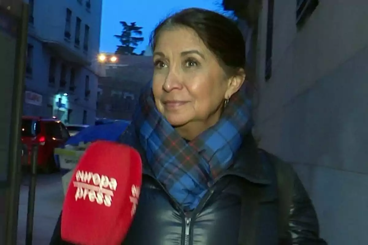 Lourdes Ornelas con bufanda azul y chaqueta negra es entrevistada en la calle por un micrófono rojo de Europa Press.