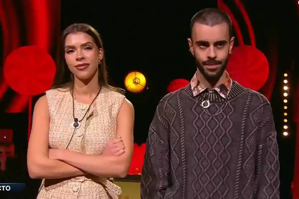 Lucía i Ruvens a Gran Hermano amb llums de fons en tons vermells i grocs.