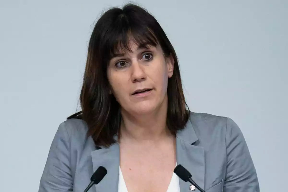 Aurora Madaula amb jaqueta grisa parlant davant de dos micròfons.