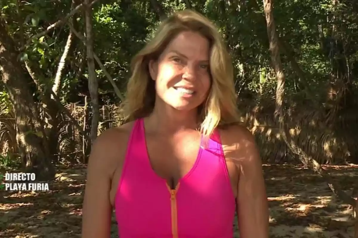 Makoke with a pink shirt is standing in a natural environment with trees and shadow in survivors.