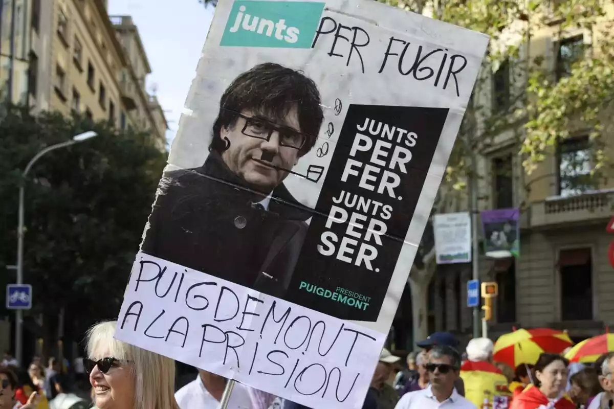Primer pla d'una pancarta a la manifestació contra l'amnistia amb el lema 'Junts per fugir, Puigdemont a presó'