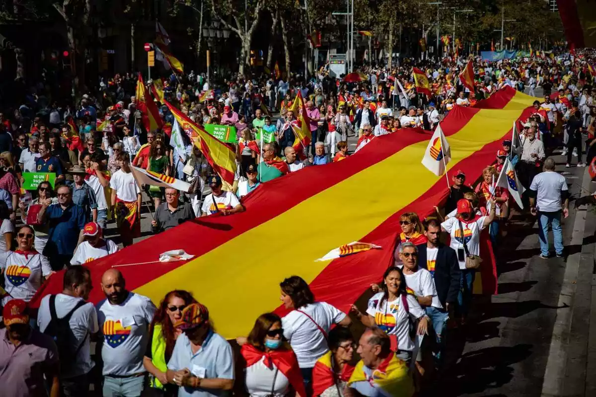 Pla general d´una manifestació constitucionalista a Barcelona. Diversos manifestants subjecten una bandera espanyola gegant mentre llueixen samarretes amb el logotip de Ciutadans d'un cor format per les banderes de Catalunya, Espanya i Europa