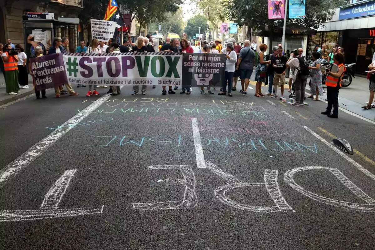 Poques desenes de persones darrere una pancarta amb el lema 'Stop Vox'