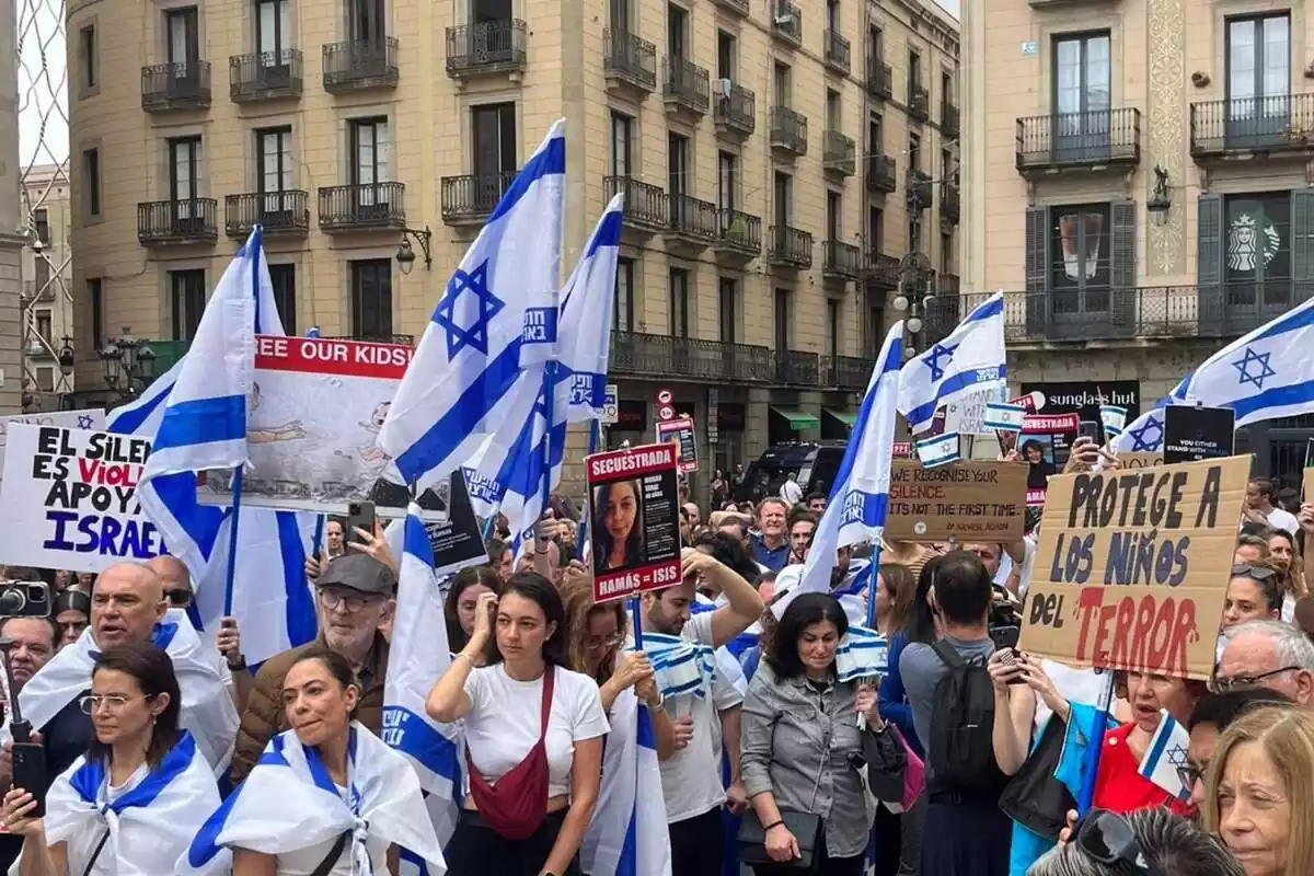 Diversos manifestants a la plaça de Sant Jaume de Barcelona lluint banderes d'Israel i pancantes amb les cares d'alguns dels segrestats per Hamàs
