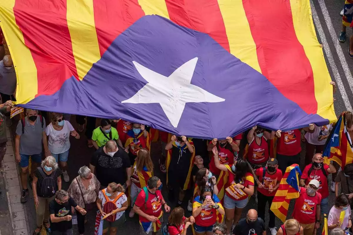 Diverses persones porten una bandera estelada durant la manifestació organitzada per l'Assemblea Nacional Catalana (ANC) amb motiu de la Diada, dia de Catalunya, a 11 de setembre de 2021, a Barcelona