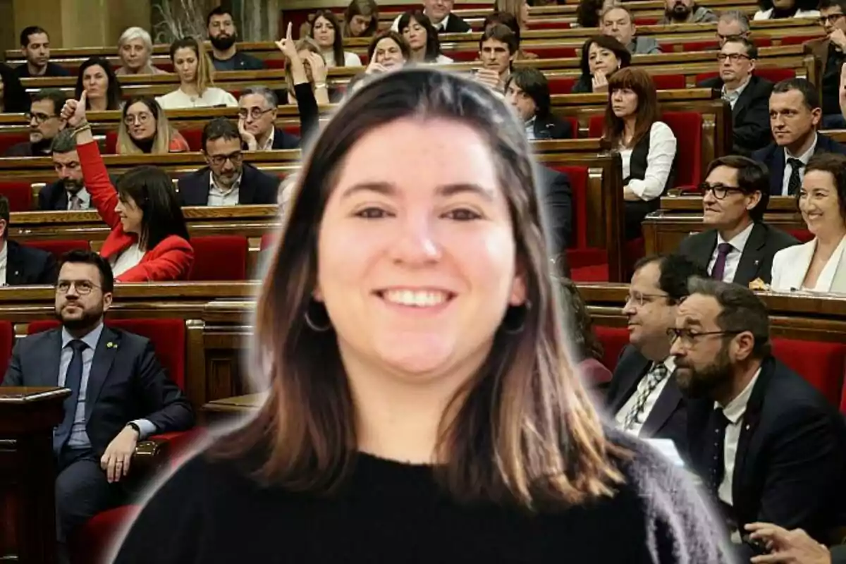 Una dona somrient en primer pla amb una audiència a un parlament de fons.