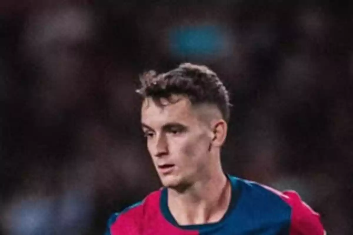 Un jugador de futbol amb uniforme blau i vermell en un camp de joc. Un jugador de futbol amb uniforme blau i vermell en un camp de joc.