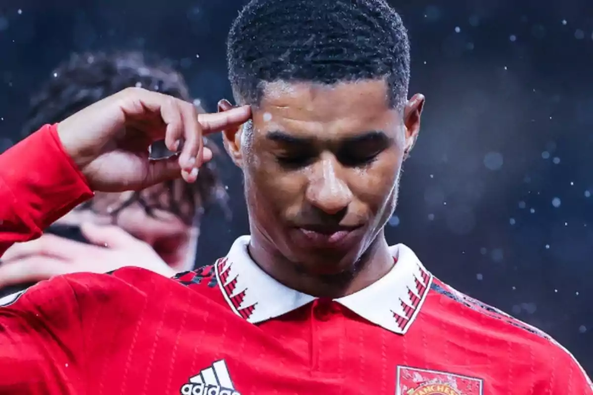 A player in a red uniform touches his temple with his index finger in a gesture of concentration. A player in a red uniform touches his temple with his index finger in a gesture of concentration.