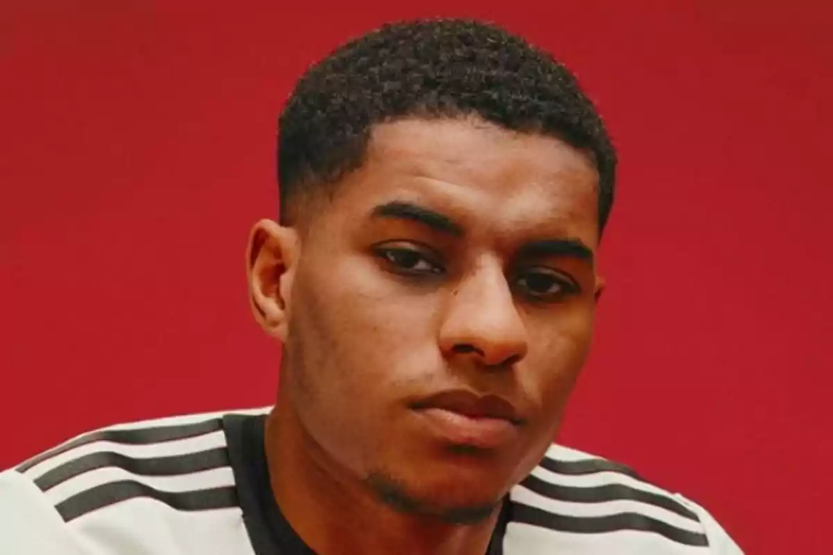 A man in a black and white jersey posing in front of a red background. A man in a black and white jersey posing in front of a red background.