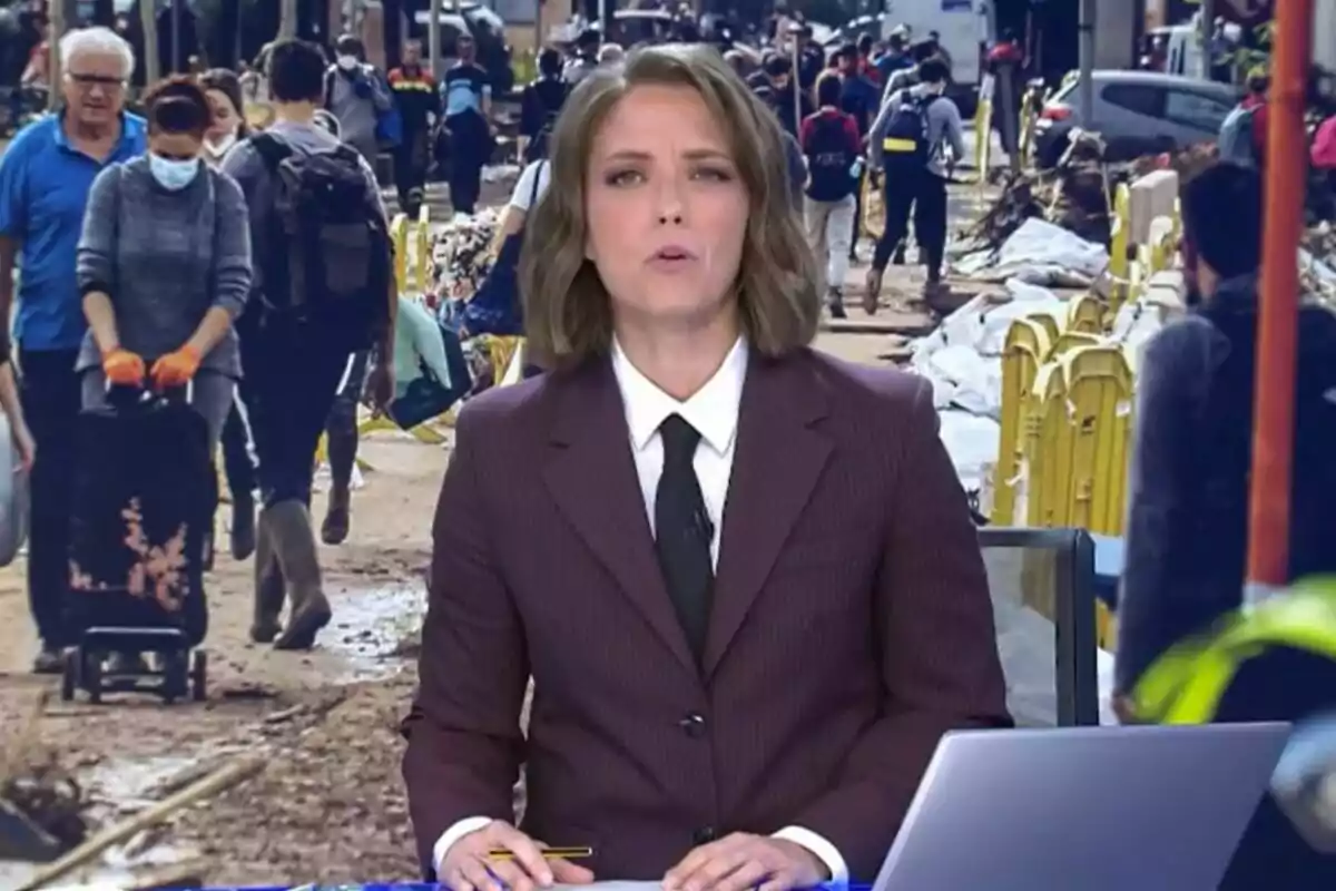 María Casado a Informatius Telecinco en un estudi amb una imatge de fons que mostra persones caminant per un carrer concorregut.