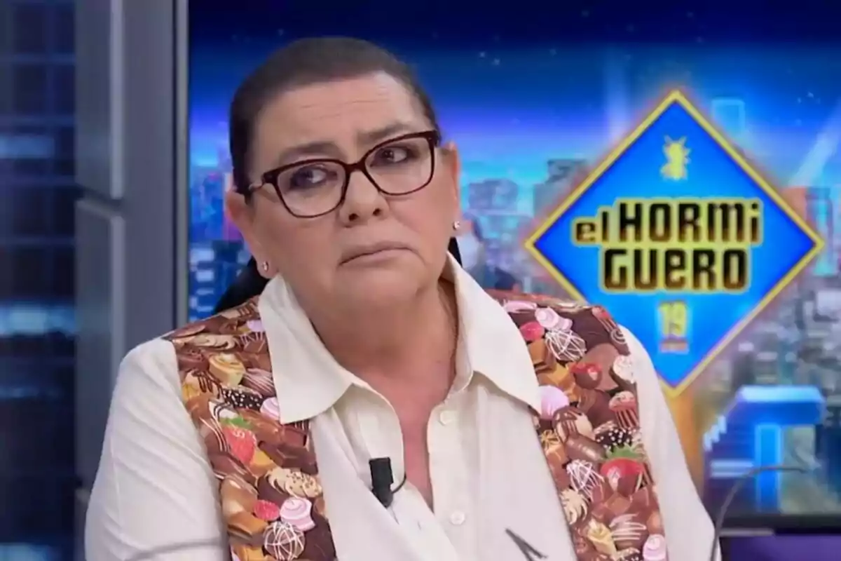 María del Monte amb ulleres i armilla acolorida està en un plató de televisió amb el logotip de "El Hormiguero" de fons.