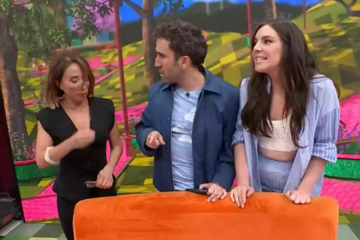 María Patiño, Aitor Albizia i Inés Hernand conversen animadament en un plató acolorit amb un fons d'arbres i patrons geomètrics de La Família de la Tele. María Patiño, Aitor Albizia i Inés Hernand conversen animadament en un plató acolorit amb un fons d'arbres i patrons geomètrics de La Família de la Tele.