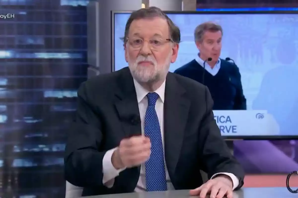 Maríano Rajoy amb barba i ulleres està assegut a 'El Hormiguero', parlant mentre gesticula amb la mà, i al fons es veu una pantalla amb una altra persona parlant en un faristol.