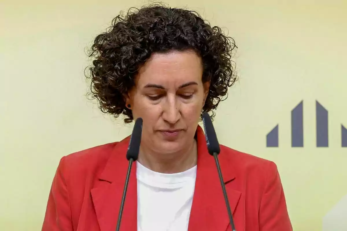 Marta Rovira amb jaqueta vermella parlant davant de dos micròfons.