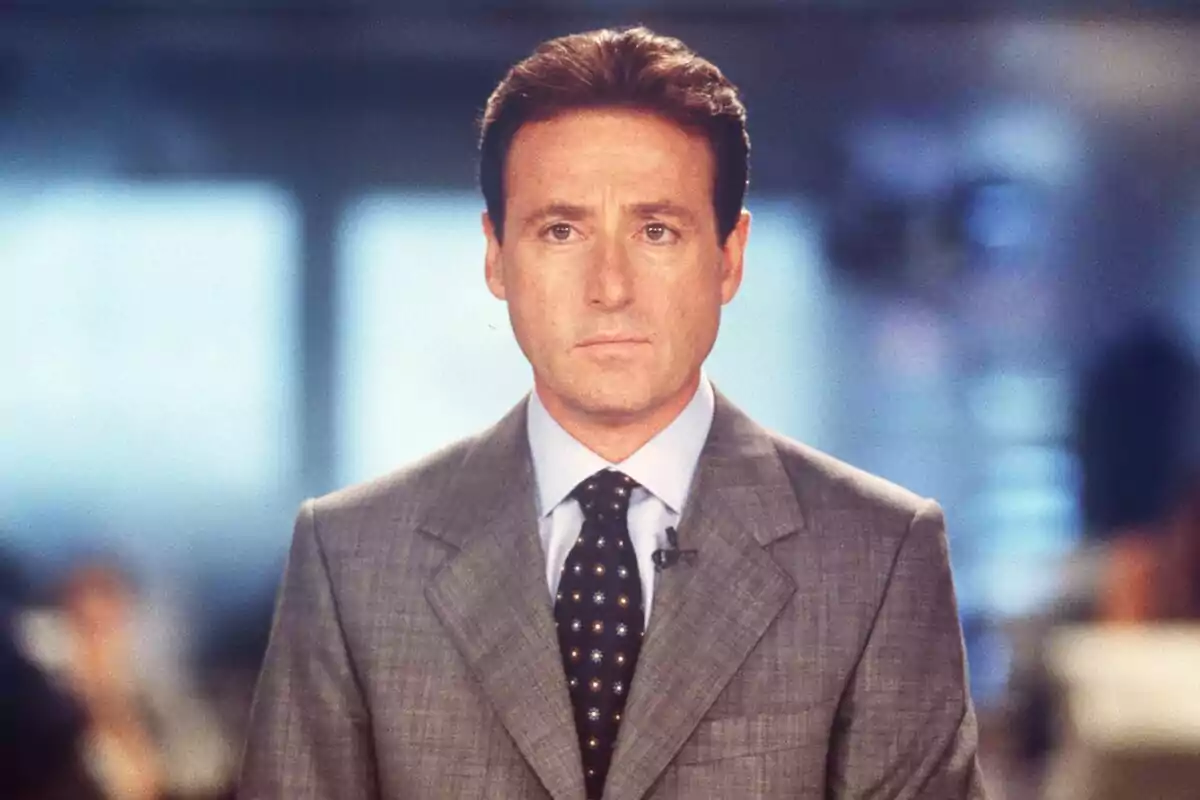 Matías Prats amb vestit gris i corbata fosca està dret en un entorn d'oficina amb fons desenfocat a Antena 3 Notícies.