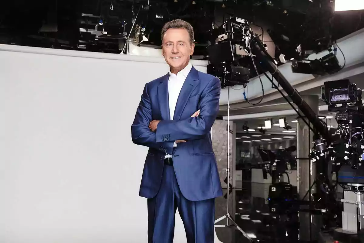 Matías Prats dret amb vestit blau i camisa blanca, amb els braços creuats, en un estudi de televisió envoltat de càmeres i equip de gravació a Antena 3 Notícies. Matías Prats dret amb vestit blau i camisa blanca, amb els braços creuats, en un estudi de televisió envoltat de càmeres i equip de gravació a Antena 3 Notícies.