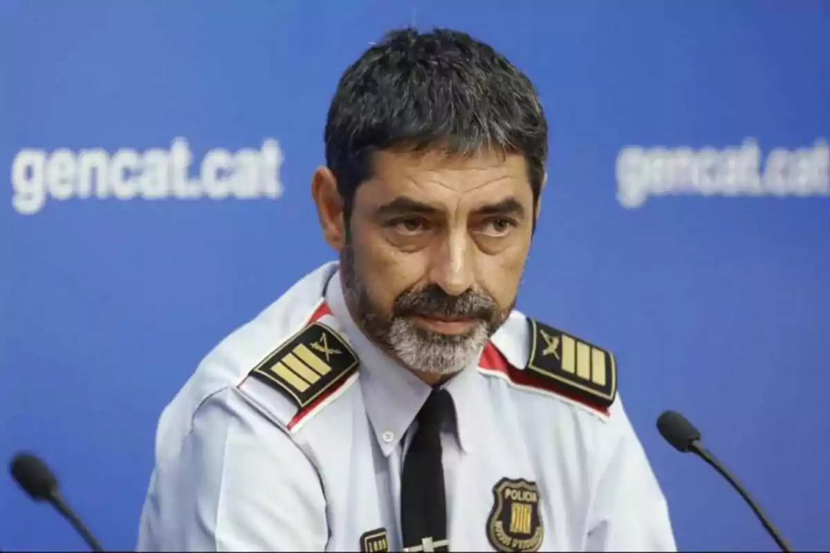 Un home amb uniforme de policia en una conferència de premsa davant d'un fons blau amb el text “gencat.cat”.