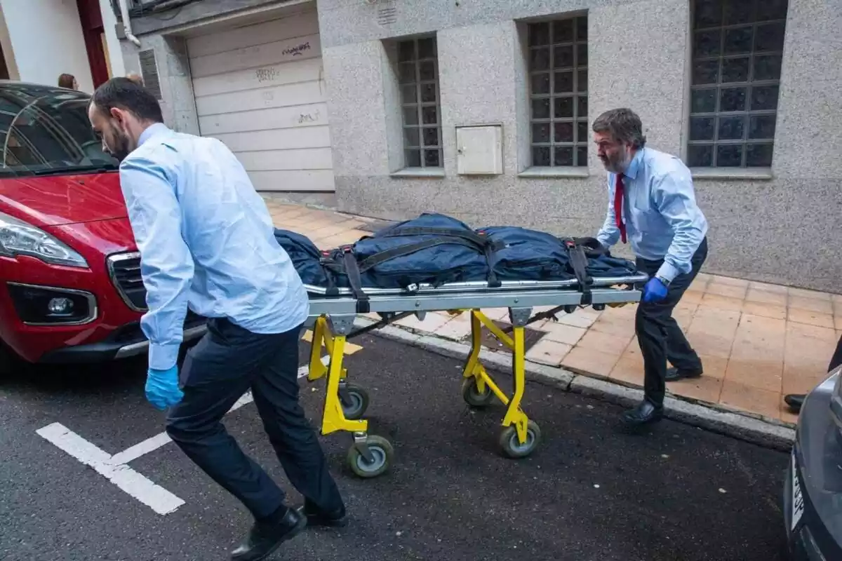 Dos metges portant-se el cos d'una dona en una llitera
