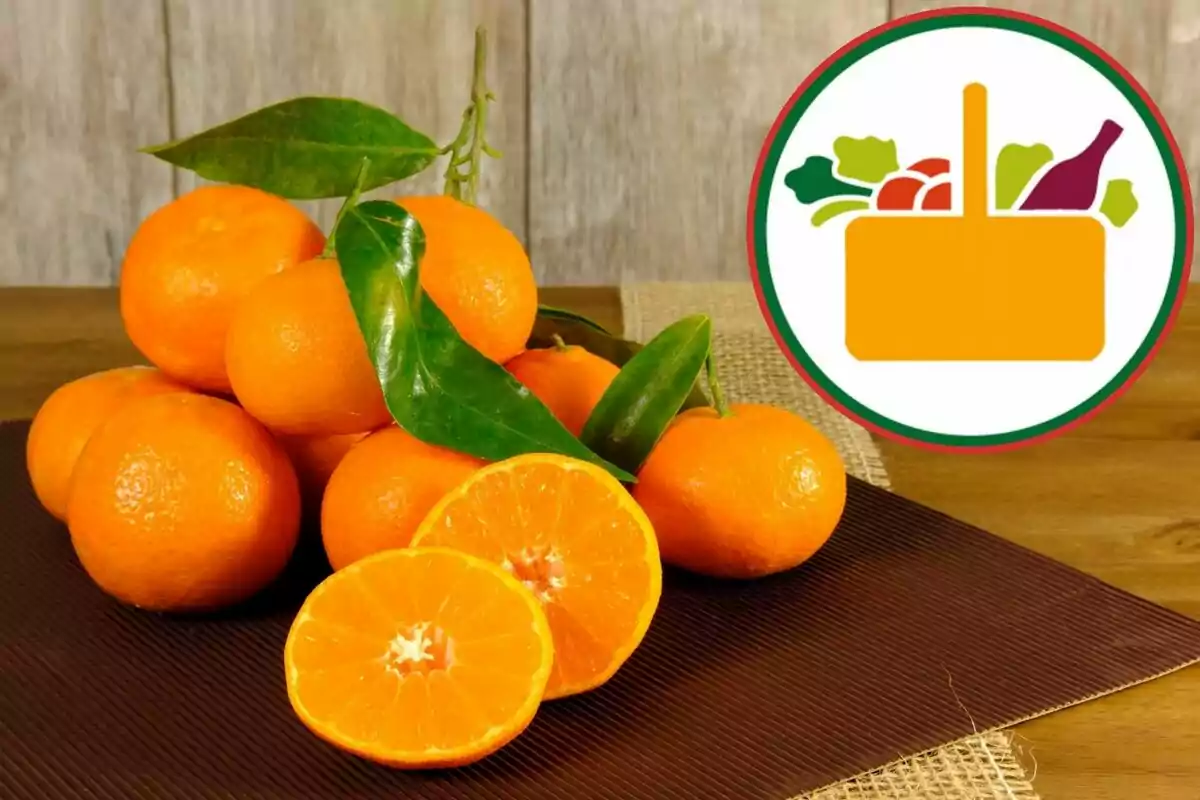 Mandarines frescos amb fulles verdes sobre una taula al costat d’un logotip de cistella d’aliments Mandarines frescos amb fulles verdes sobre una taula al costat d’un logotip de cistella d’aliments