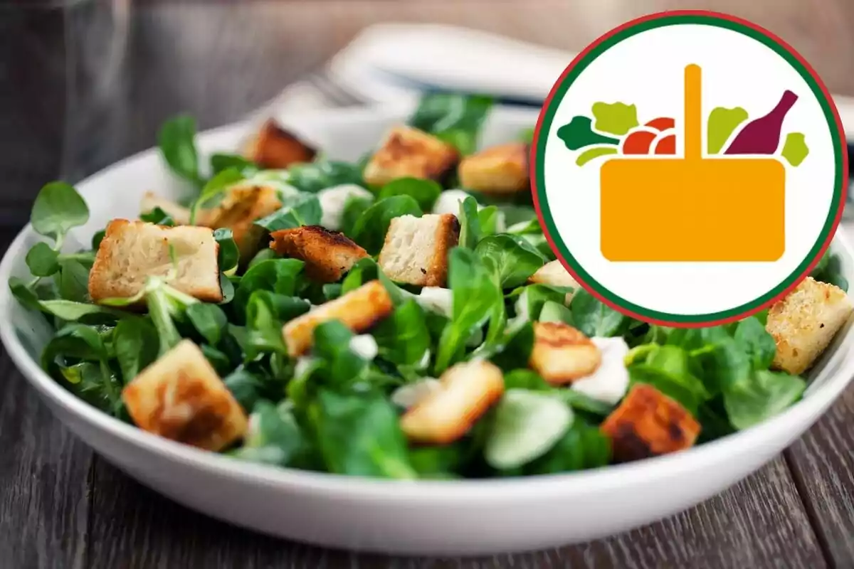 Green salad with croutons on a white plate and a food basket icon in the top right corner