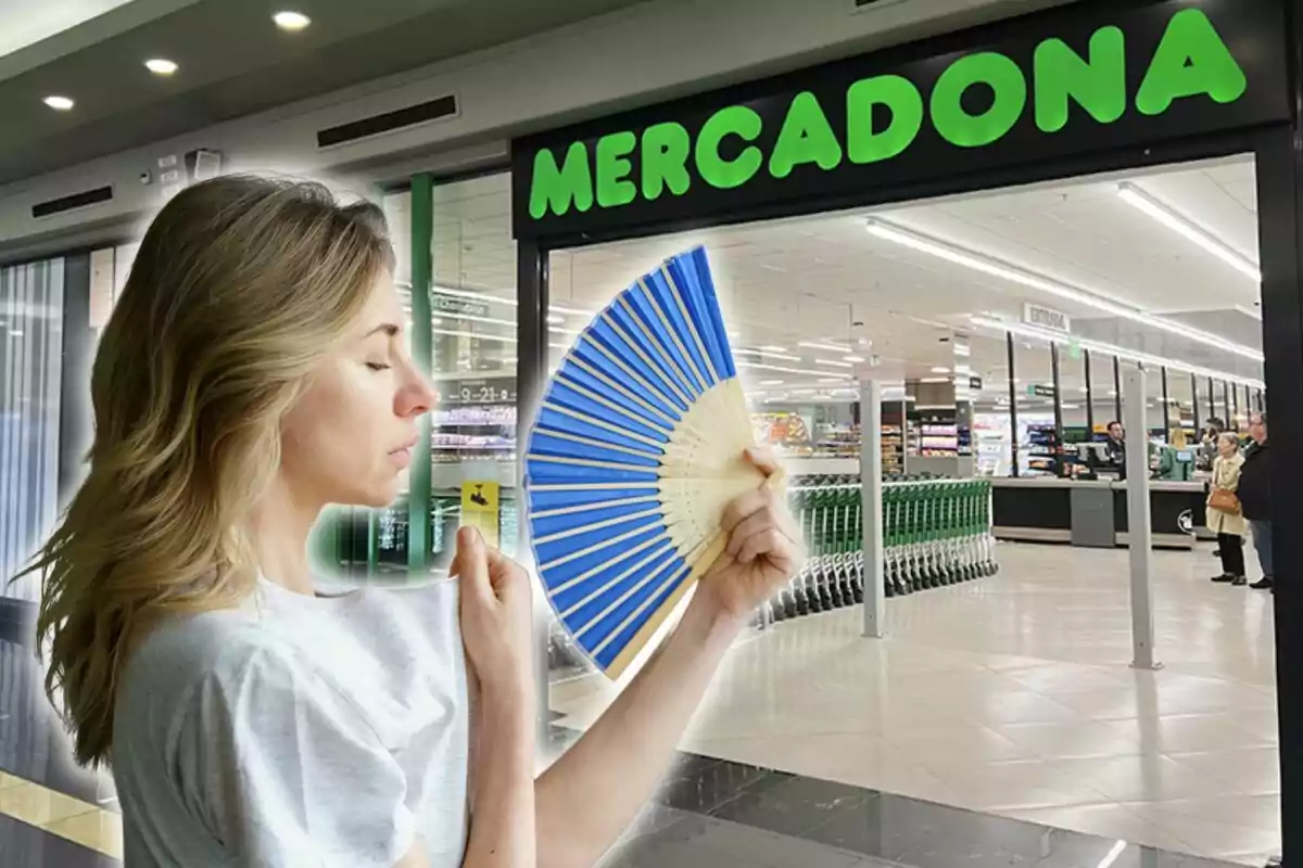 A woman with a blue fan is standing in front of the entrance to a supermarket.
