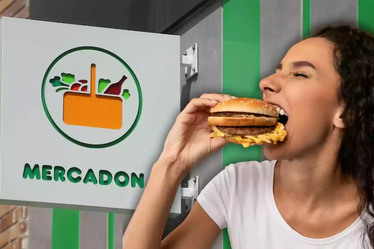 Una persona comiendo una hamburguesa frente a un cartel de supermercado.