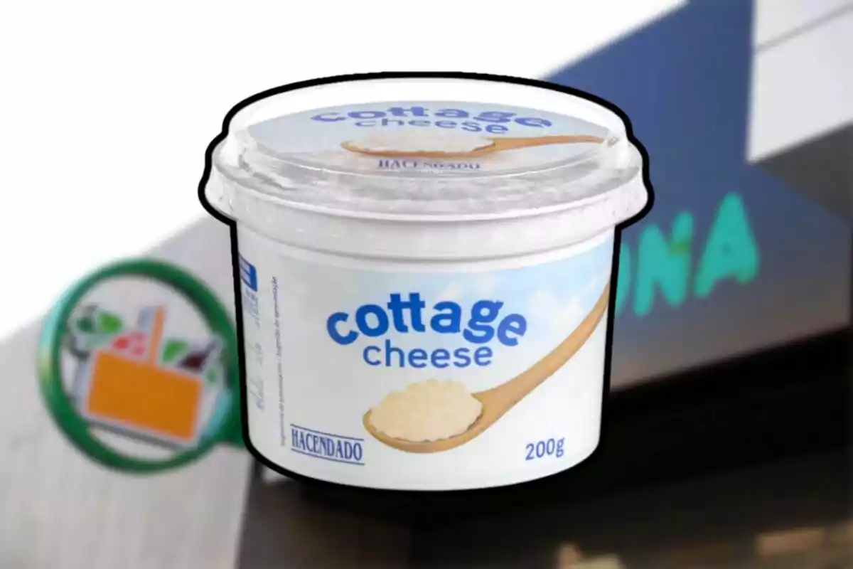 Envàs de formatge cottage de la marca Hacendado amb una cullera de fusta il·lustrada a l'etiqueta, sobre un fons que sembla ser la façana d'un supermercat. Envàs de formatge cottage de la marca Hacendado amb una cullera de fusta il·lustrada a l'etiqueta, sobre un fons que sembla ser la façana d'un supermercat.