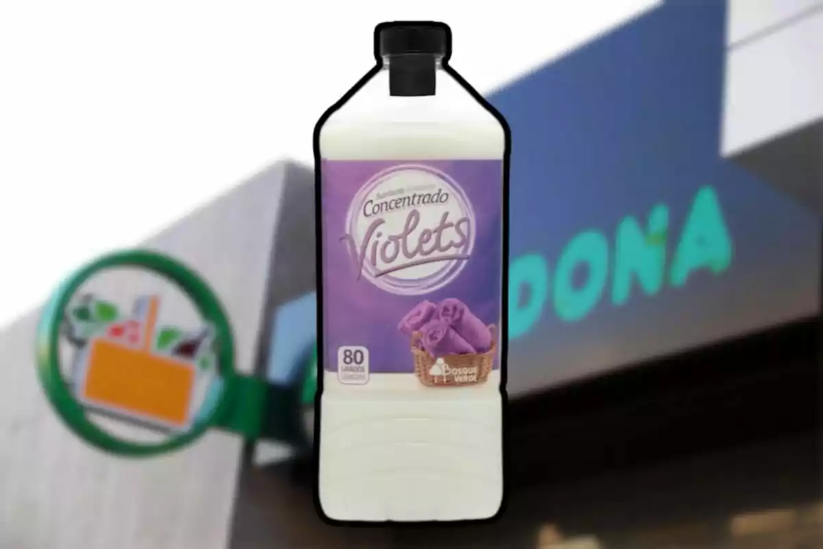 Ampolla de suavitzant concentrat amb etiqueta violeta davant d'un cartell de supermercat. Ampolla de suavitzant concentrat amb etiqueta violeta davant d'un cartell de supermercat.