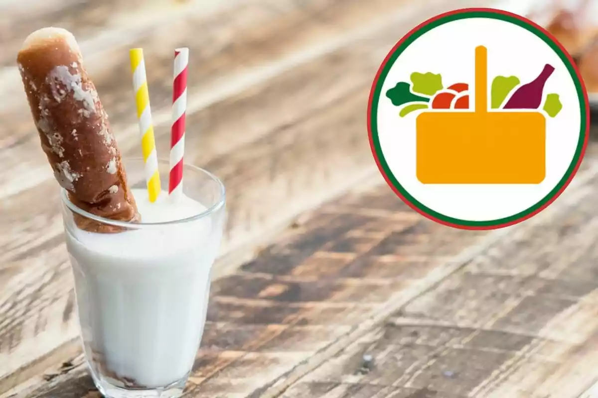 Got de llet amb un panet i dues palletes de colors sobre una taula de fusta al costat d’un logotip de cistella amb aliments Got de llet amb un panet i dues palletes de colors sobre una taula de fusta al costat d’un logotip de cistella amb aliments