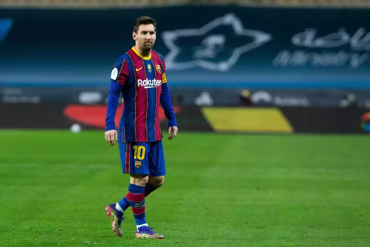 Un jugador de futbol amb uniforme blau i vermell camina pel camp durant un partit. Un jugador de futbol amb uniforme blau i vermell camina pel camp durant un partit.