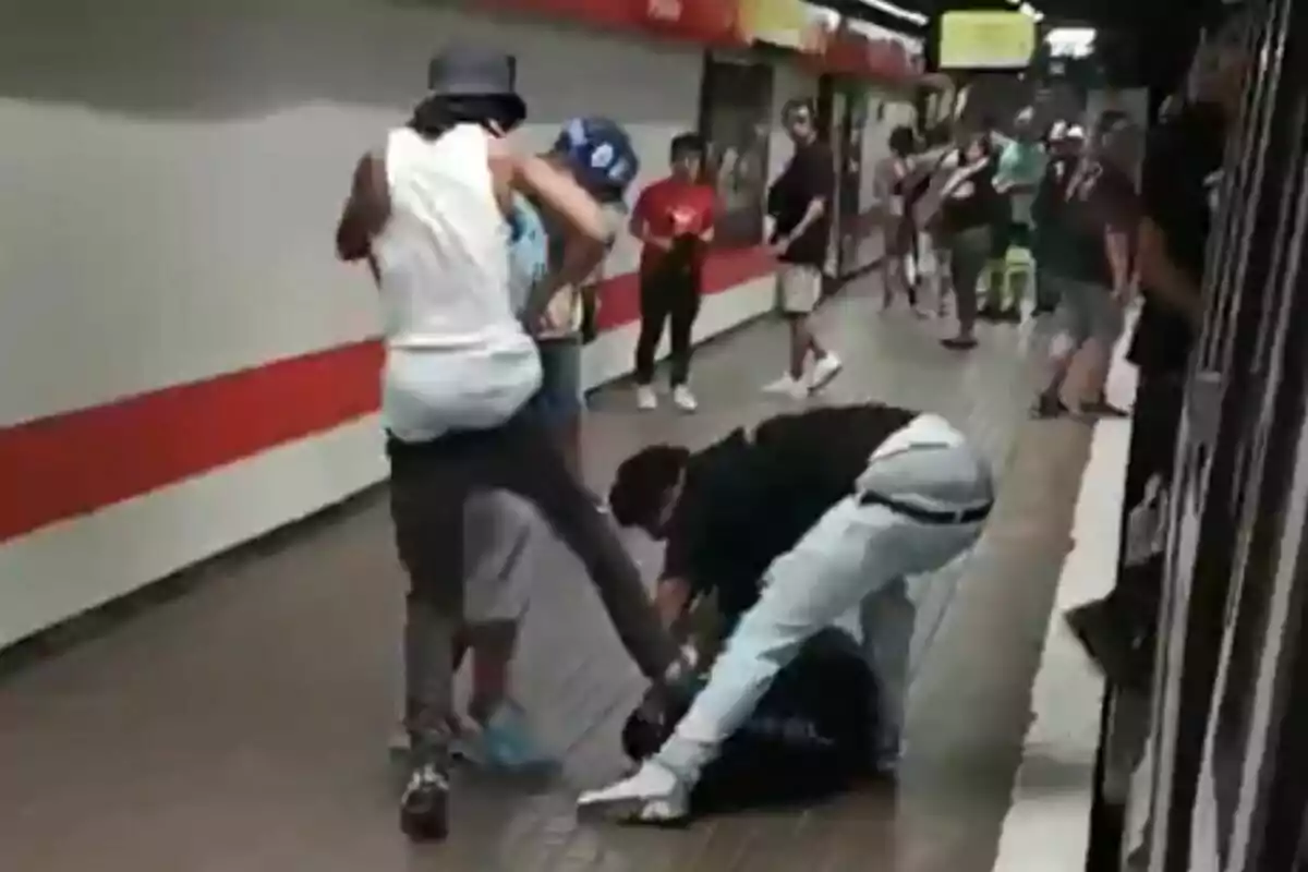 Diverses persones en una estació de metro, algunes involucrades en una baralla mentre altres observen.