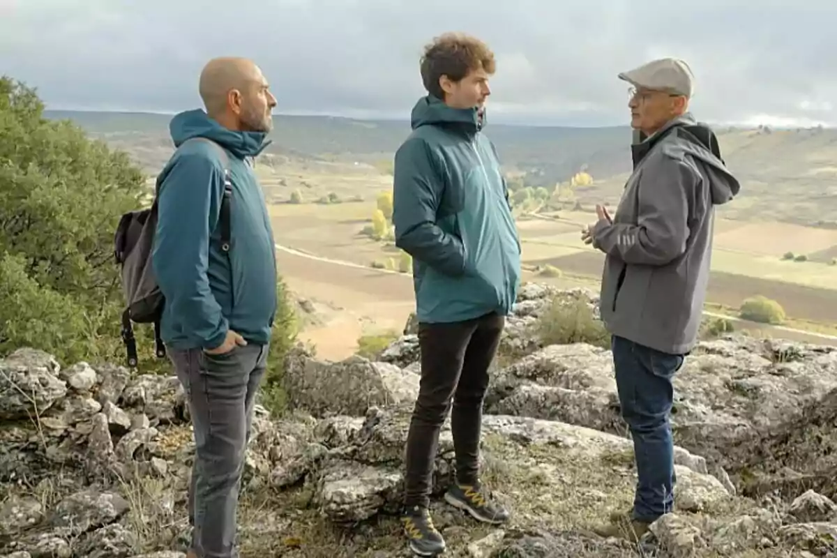 Eloi Vila al costat de Miki Núñez i una altra persona en un paisatge rural amb turons i camps al fons a Quanta Guerra!