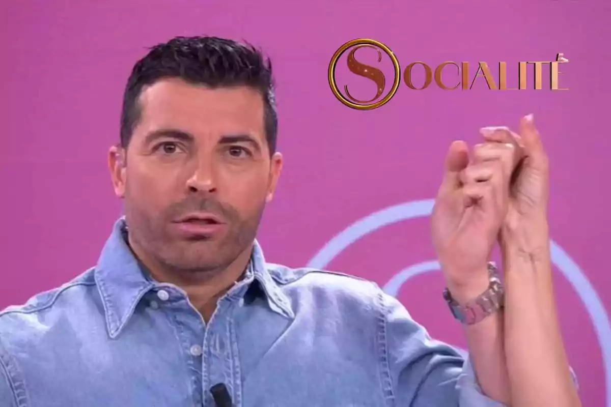 Antonio Santana con camisa de mezclilla sostiene la mano de otra persona frente a un fondo rosa con el logotipo de "Socialité".