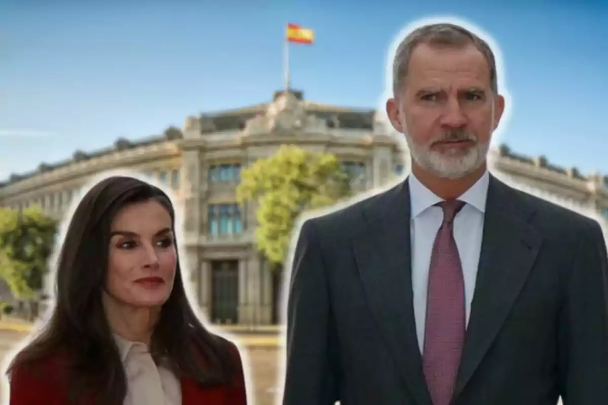 La reina Letizia y Felipe VI posan frente a un edificio con una bandera española ondeando en la parte superior.