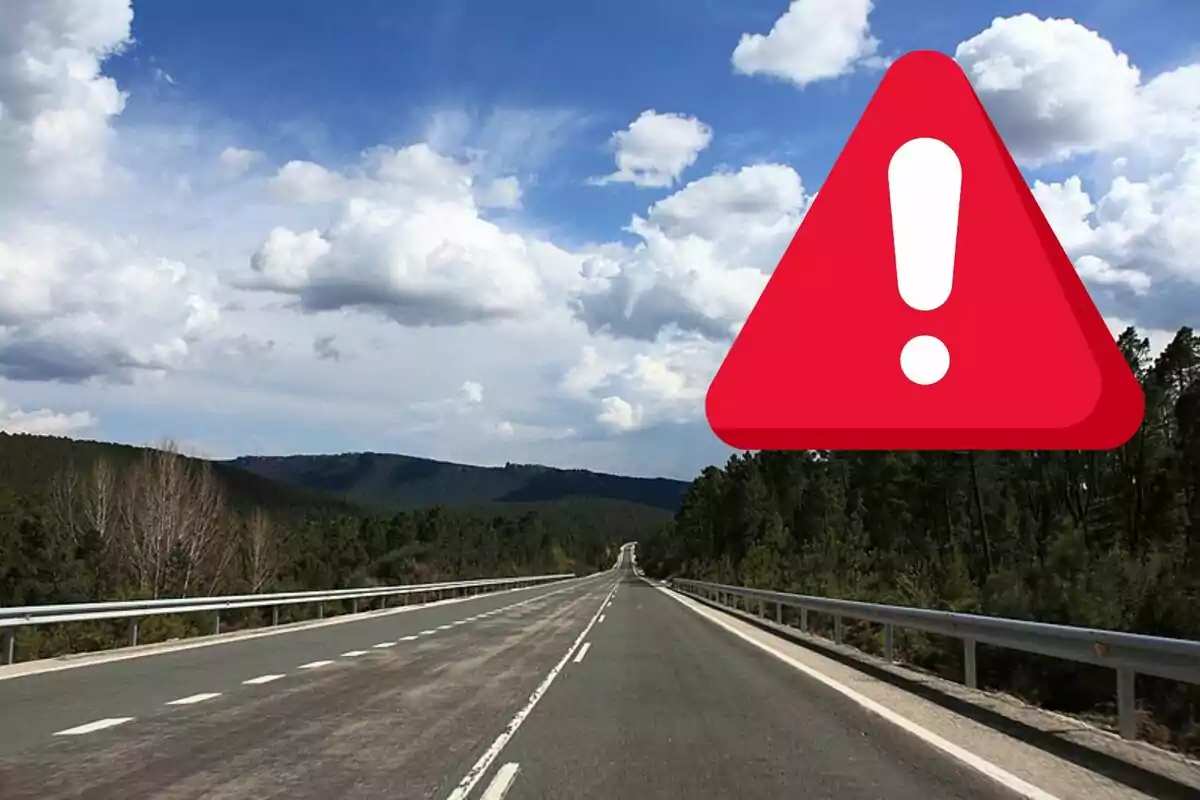 Carretera recta rodeada de árboles con un cielo parcialmente nublado y un gran icono de advertencia rojo con un signo de exclamación.